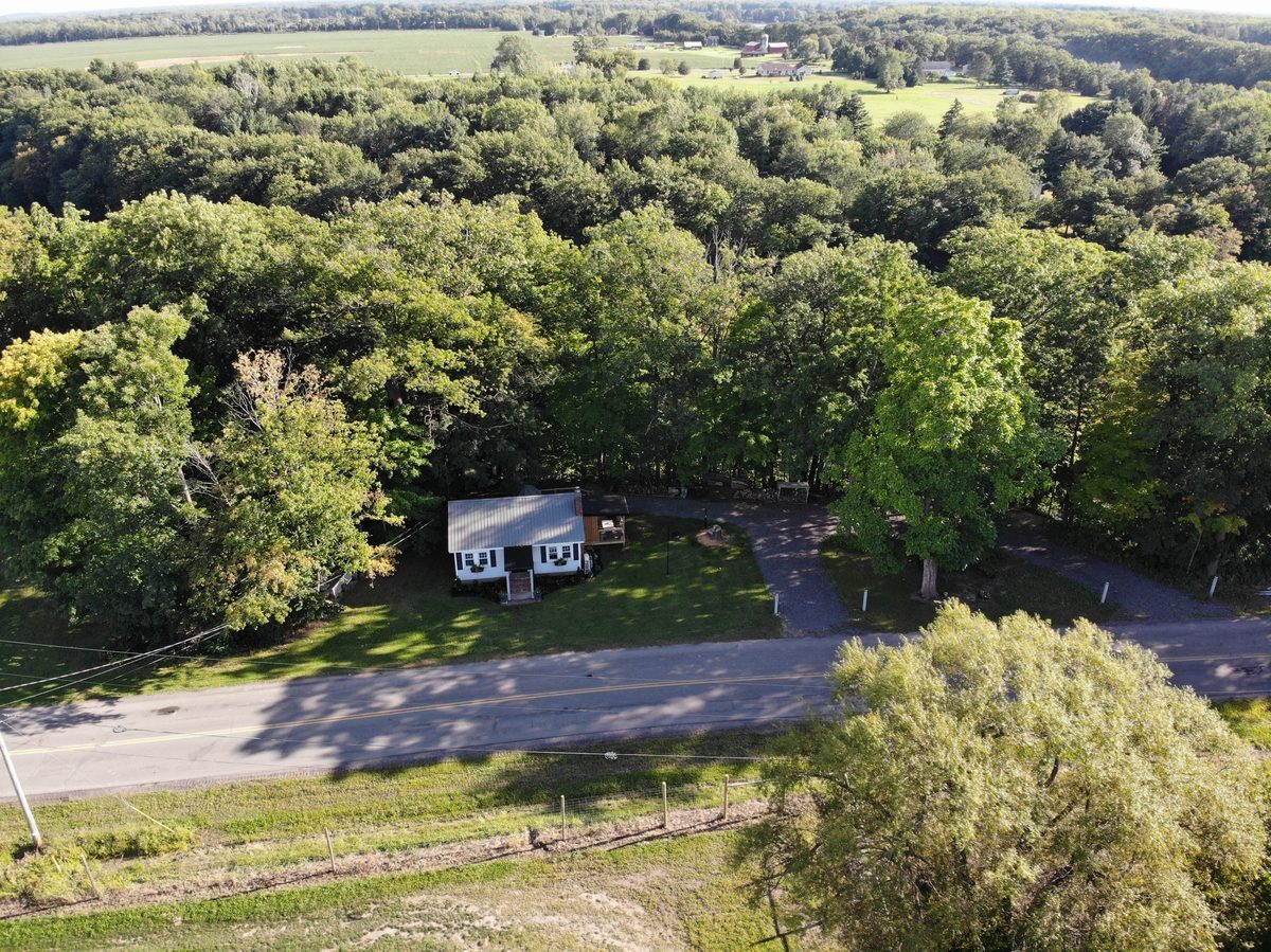 Aerial view of the cottage nestled among mature trees along the road