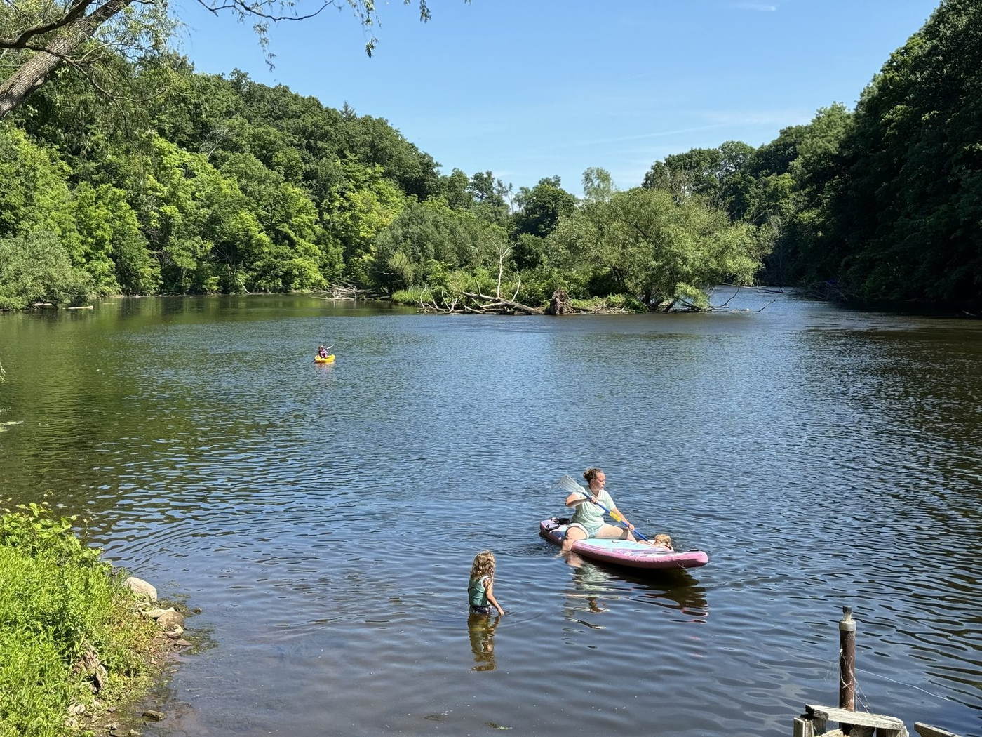 Family kayaking, paddleboarding, and swimming on the Oak Orchard River